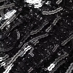 Detail of silver and black sequins on black mesh fabric with geometric embroidery patterns