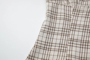 Detailed macro view of the beige and brown checkered pattern fabric and waist stitching