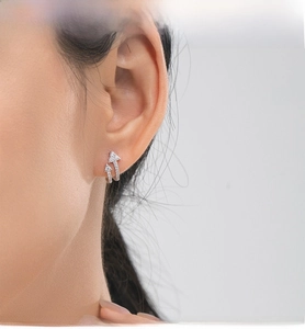 Detail of silver double arrow stud earrings with micro-pave white zircon on ear model