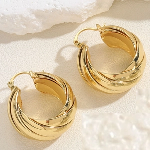 Detailed close-up of gold layered hoop earrings on textured white decorative stones