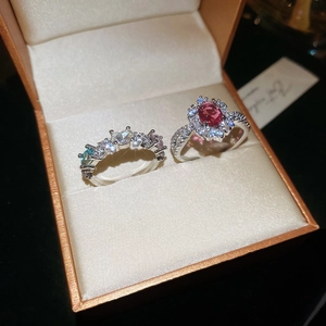 Close-up of elegant oval red gemstone ring and colorful zircon bands in a jewelry box
