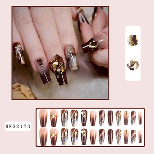 Detail of coffee brown marble press-on nails with gold foil and 3D crystal accents