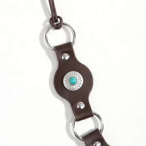 Detail of vintage brown leather belt with turquoise stone and silver floral engraving