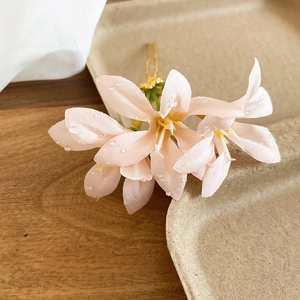 Detail of pink fabric flower hair pin with dewdrop beads on a gold metal base