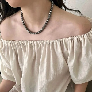 Detail of dark grey pearl necklace on neck showing metallic luster and elegant drape