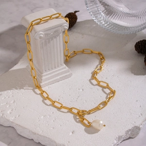 Collier chaîne trombone doré minimaliste avec un pendentif perle baroque sur une colonne