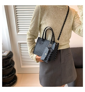 Détail d'un sac cabas noir à motifs avec une pochette assortie porté par un mannequin
