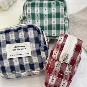 Detail view of plaid fabric storage bags with silver zippers in blue green and red