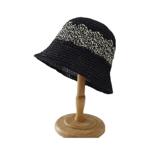 Handwoven black hollow straw bucket hat with beige wavy ribbon trim for sun protection