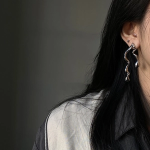 Detail view of silver asymmetrical twisted drop earrings worn by a fashion model