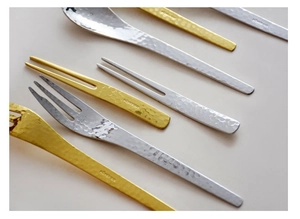 Close-up of gold and silver stainless steel cutlery set with unique hammered texture finish