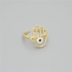 Detailed shot of golden Hamsa Hand ring with a white enamel Evil Eye on a grey background