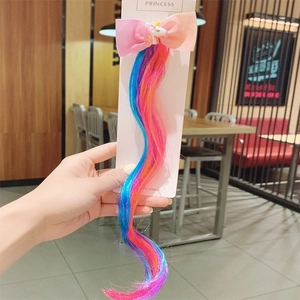 Close-up of unicorn hair clip with pink bow and blue-pink gradient colored extensions
