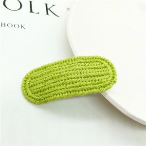 Macro shot of bright green knitted hair clip showing detailed textured weave and fabric