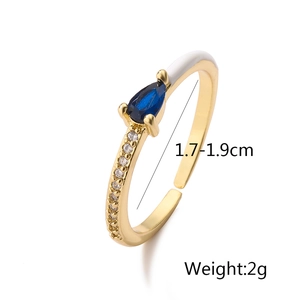 Detail view of 18K gold ring with blue teardrop gemstone and white enamel accent