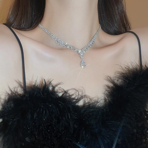 Detailed close-up of a silver water drop pendant necklace with sparkling diamonds