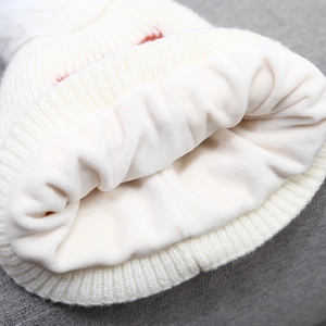 White knit winter hat for kids featuring soft fleece lining and fluffy pom-pom detail