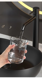 Detail of 290ml transparent glass cup being filled with water from a matte black faucet