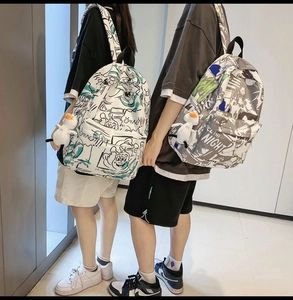 Detail of waterproof graffiti backpacks with duck charms in white and grey colors