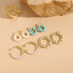 Detail of 14K gold plated earrings with freshwater pearls and turquoise on natural rocks