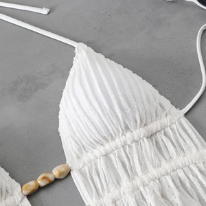 Detail of white textured bikini top featuring pleated fabric and marble-patterned beads