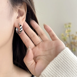 Chic zebra pattern hoop earrings with black enamel and silver finish shown on a model