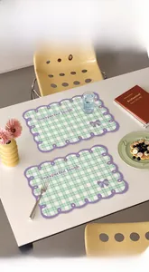 Close-up of green checkered leather placemat with purple scalloped edges and bow detail