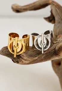 Detalle de anillos anchos dorados y plateados con diseño de hebilla OT en madera