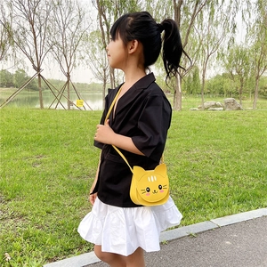Cute yellow cat-shaped crossbody purse for kids shown in an outdoor lifestyle setting.