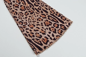 Detailed close-up of leopard print sheer mesh fabric with flared cuffs and ruffled hem edges