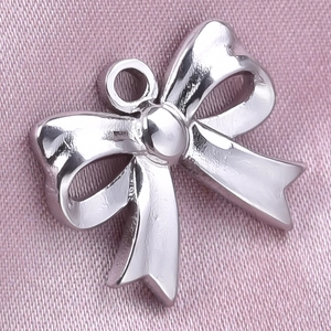 Detailed macro view of a silver bow pendant on pink silk with a connector ring