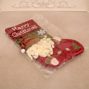 Detail view of a red linen Christmas stocking with 3D Santa and tree in clear packaging