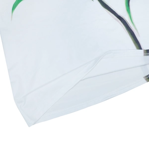 Close-up of white dress fabric showing high-quality stitching and green leaf print detail