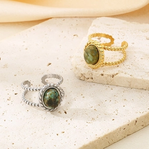 Vintage stainless steel open ring with green stone on a minimalist stone background