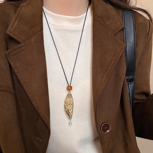 Minimalist leather leaf pendant necklace with hammered gold finish on a model