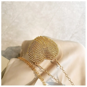 Macro shot of gold heart-shaped evening bag with sparkling rhinestones and metal chain