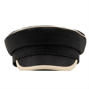 Detail of black faux leather beret featuring textured reptile skin pattern and beige piping