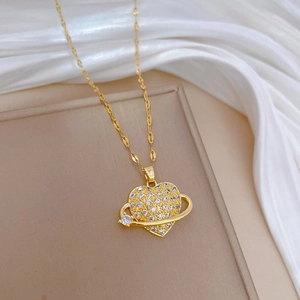 Gold heart planet necklace with sparkling cubic zirconia on an elegant beige tray