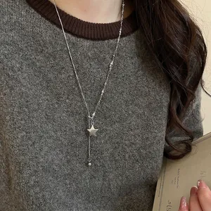 Minimalist silver star pendant Y-necklace for women on a dark grey knit sweater