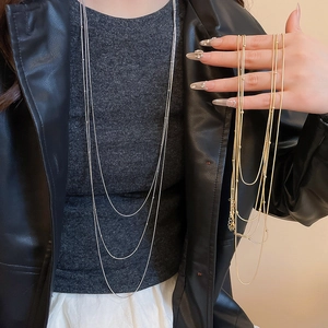 Detail of layered silver and gold tassel necklaces with beads shown on a leather jacket