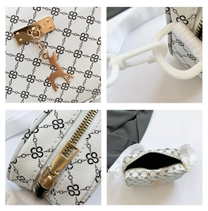 Detail of white crossbody bag with chain print, golden deer charm and zipper close-up
