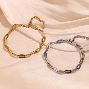 Detail of 14K gold and silver stainless steel lip link anklets on beige silk fabric