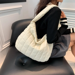 Close-up of beige quilted cotton tote bag with diamond pattern on a model shoulder