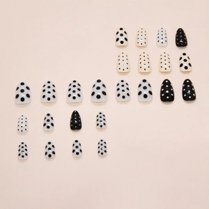 Chic black and white polka dot almond press-on nails set on a pink background