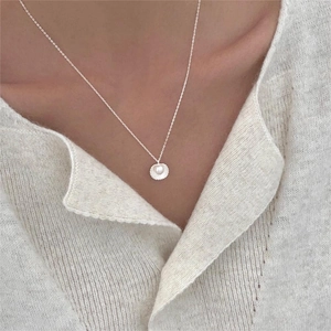 Detailed view of 925 sterling silver shell pendant with a delicate pearl on a knit sweater