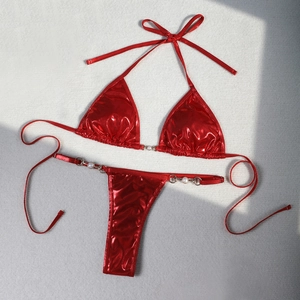 Detail of red metallic bikini with pearl accents and tie-side thong on grey surface