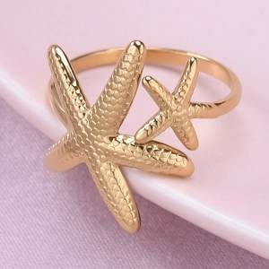 Macro view of gold-plated starfish ring detail with textured grains and dual star design