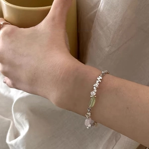 Detail of silver beaded bracelet with light green and pink crystals worn on wrist