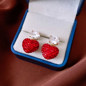 Vue détaillée de boucles d'oreilles cœur avec cristaux rouges et finition dorée élégante