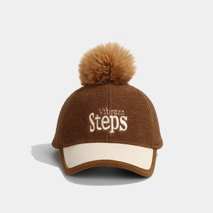 Detail of vibrant steps embroidery on kids winter baseball cap with faux fur pompom